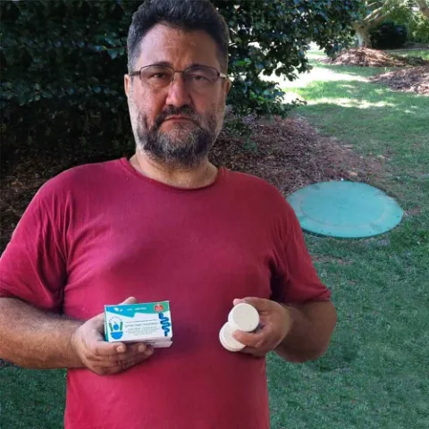 Septifix customer holding a box and tablet in his backyard near a septic lid